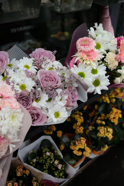 A collection of fresh floral bouquets arranged with a variety of flowers including soft pink roses, white daisies with green centers, and light pink chrysanthemums, wrapped in pastel pink and purple t